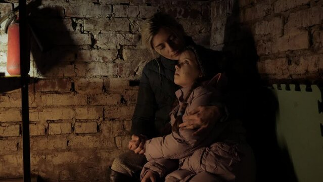 Ukraine war. Shelter. Bunker, Ukrainian mother and child in the basement. With fear suffering, praying, war conflict. Refuge.bomb shelter. Stop War sitting in the shelter, basement. Crisis, peace