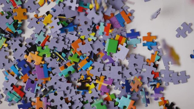Falling jigsaw puzzles randomly fill the white background. Slow motion. Close-up