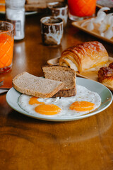 Fried eggs and bread in white plate for breakfast on wooden table