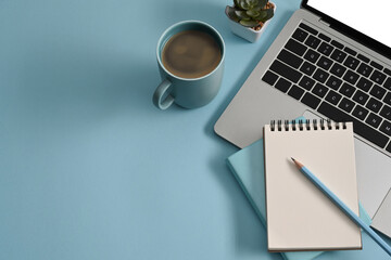Creative designer workplace with computer laptop, coffee cup and succulent plants on blue...