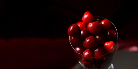 Top view of a fresh cherry or merry close-up on a black background in a low key. Panoramic photo. A...