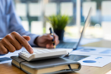 business office worker sitting at a desk using a calculator to calculate Financial data analysis and market growth report graph.