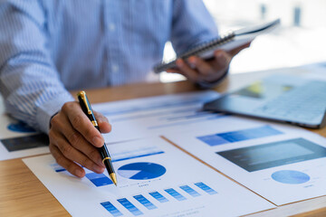 Businessman sitting at desk using laptop and taking notes, analyzing financial data and graphing market growth reports. and investment results, analytical concepts and financial investments.