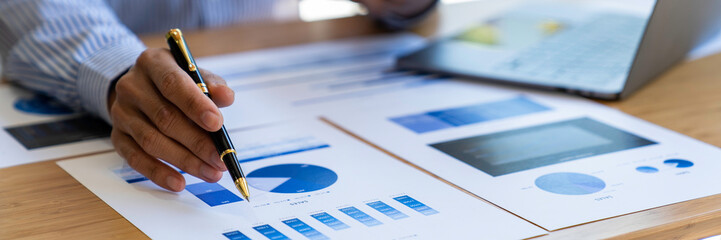 Businessman sitting at desk using laptop and taking notes, analyzing financial data and graphing market growth reports. and investment results, analytical concepts and financial investments.