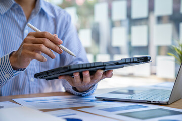 Businessman sitting at desk using laptop and taking notes, analyzing financial data and graphing market growth reports. and investment results, analytical concepts and financial investments.