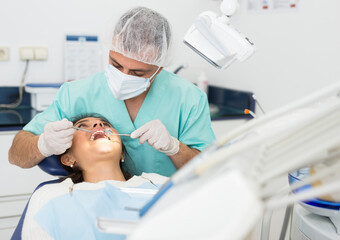 Portret of male dentist and woman patient sitting in medical chair during checkup at dental clinic...