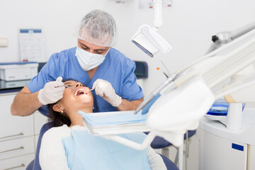 Portret of male dentist and woman patient sitting in medical chair during checkup at dental clinic office