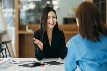 Two diverse serious businesswomen discussing business project working together in office, serious female advisor and client talking at meeting, focused executive colleagues brainstorm sharing ideas