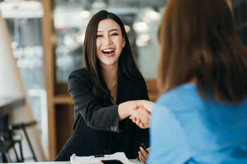 Portrait young Asian woman interviewer and interviewee shaking hands for a job interview .Business...