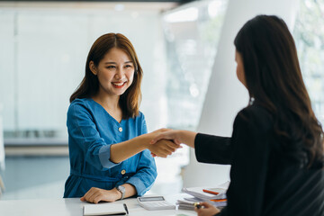 Portrait young Asian woman interviewer and interviewee shaking hands for a job interview .Business people handshake in modern office. Greeting deal concept