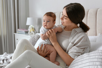 Young woman with her little baby on bed at home