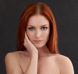 Her perfect skin compliments her natural beauty. Portrait of a gorgeous young redheaded woman against a black background.