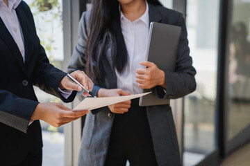 Joyful corporate trainer telling newcomer about work in company. Happy business woman holding...