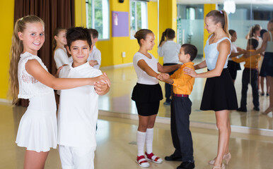 Glad adult children enjoying of partner dance in class