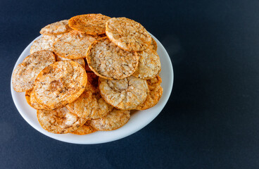 Brown rice chips on a plate against a dark background