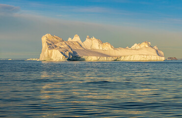 Midnightsun over a huge iceberg floating in the sea of Disko Bay, Greenland 