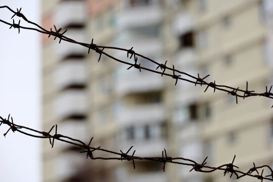 Barbed wire on residential building background. Concept of war and security in city