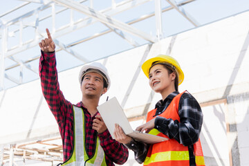 Asian engineer foreman worker man and woman working at building construction site use laptop and talking with radio