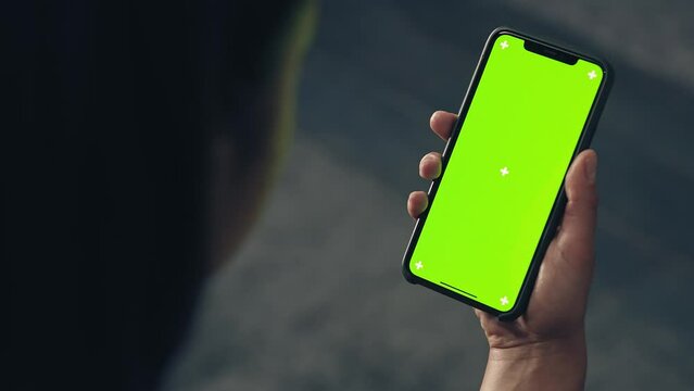 back view of fitness woman using green screen smart phone at home. Woman preparing for workout using smart phone.Woman using mobile phone while resting during fitness training