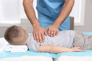 Fototapeta na wymiar Orthopedist massaging child's back in clinic, closeup. Scoliosis treatment