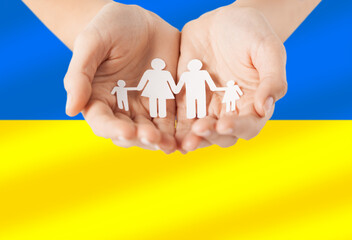 national, patriotic and charity concept - close up of hands holding family icon over colors of flag of ukraine on background