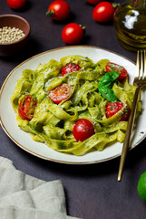 Linguini pasta with pesto sauce, tomatoes and cheese. Healthy eating. Vegetarian food. Italian cuisine.