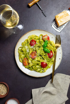 Linguini pasta with pesto sauce, tomatoes and cheese. Healthy eating. Vegetarian food. Italian cuisine.