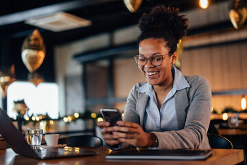 Smiling African-American woman, laughing at the joke she received on her phone.