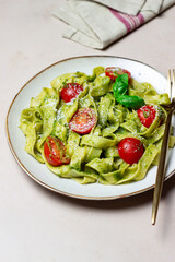 Linguini pasta with pesto sauce, tomatoes and cheese. Healthy eating. Vegetarian food. Italian cuisine.