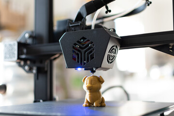 Detail of a 3D printer printing a model with a gold biodegradable PLA filament, ecofil, blue light