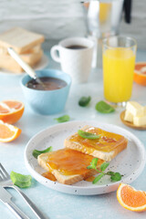 Sandwiches with marmalade, orange juice and coffee ready for breakfast