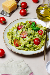 Linguini pasta with pesto sauce, tomatoes and cheese. Healthy eating. Vegetarian food. Italian cuisine.