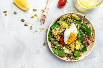 Keto diet plate quinoa, avocado, egg, tomatoes, spinach and sunflower seeds on light background. Healthy food, ketogenic diet, diet lunch concept, place for text, top view