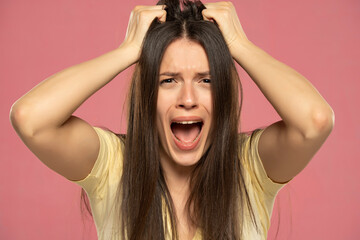 Closeup portrait stressed frustrated woman screaming having temper tantrum isolated on pink...