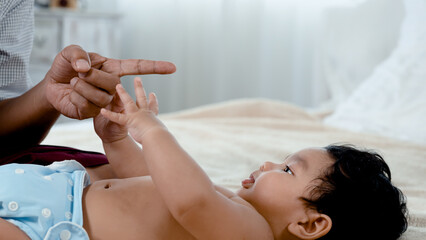 4 month old Asian newborn baby plays with a single father. Try to put your hand over your father's finger that extends to him. Concept Happy Family