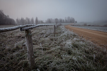 gravel road and old wooden fence on a misty cold day
