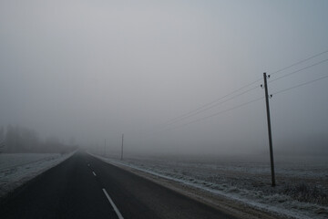 empty road on a foggy cold day with electicity poll