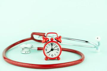 stethoscope with red clock on blue background copy space