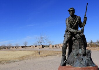 
 a buffalo soldier statue  at the nineteenth century  united states army post  of fort selden historic site near radium springs,  in dona ana county, new mexico, on a sunny winter day 