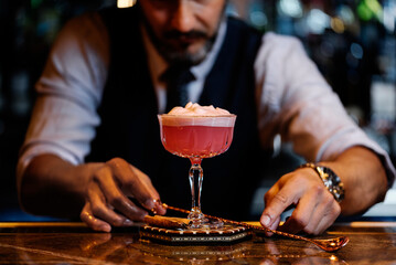 Barman is making cocktail at night club.