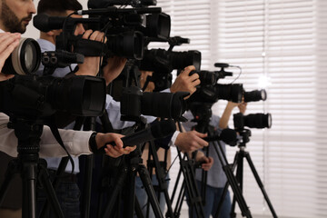 Group of journalists with cameras waiting for official person indoors, closeup