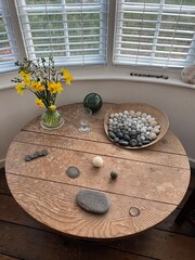 Interior Kettles Yard Cambridge wood vintage table with artefacts including pattern of natural stones a fresh flower vase ornament art statues placed in front of window with day light flat lay view  