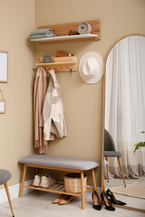 Hallway interior with stylish furniture, accessories and wooden hanger for keys on beige wall