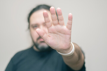 Obraz premium An unshaven man with bracelets in the colors of the Japanese flag holds his hand in front of him in a gesture of denial. Selective focus on the bracelet.
