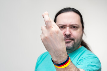 An adult, unshaven man holds his fingers crossed in front. Bracelet in the colors of the German flag. Selective focus on hand with fingers crossed.