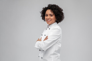 cooking, culinary and people concept - happy smiling female chef in white jacket over grey...