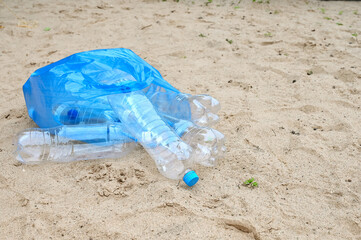 bag of plastic bottles is lying on sand. Protection of nature, ecology from pollution. World Environment Day, concept of Earth Day