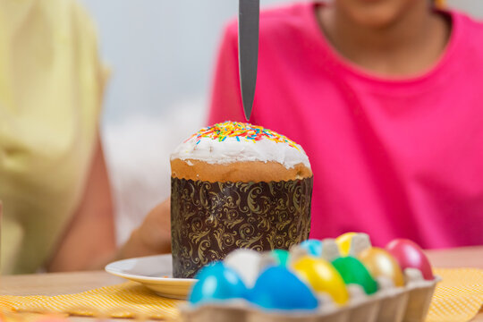 Mom Cuts An Easter Cake To Treat Her Daughter. African American Woman And Little Girl Are Sitting At Table In Festively Decorated Room At Home. Happy Easter. Close Up.