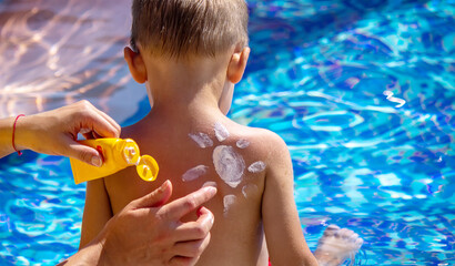 Mother puts cream on her son's back. Caring for baby skin. Sunscreens in the travel. selective focus