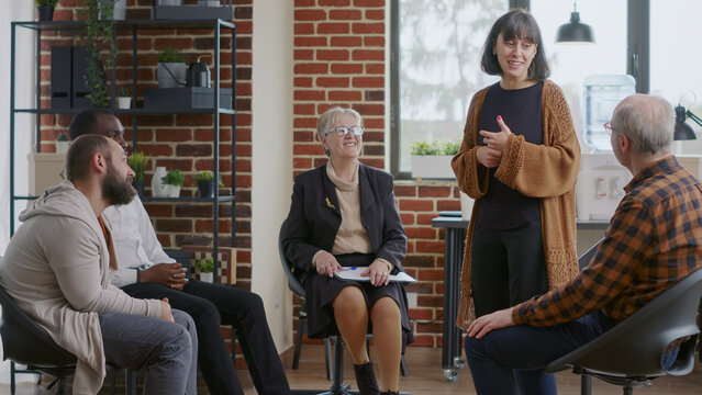 Woman sharing therapy progress with group at aa meeting and receiving applause. People clapping hands and celebrating addiction success and achievement at rehabilitation program session.